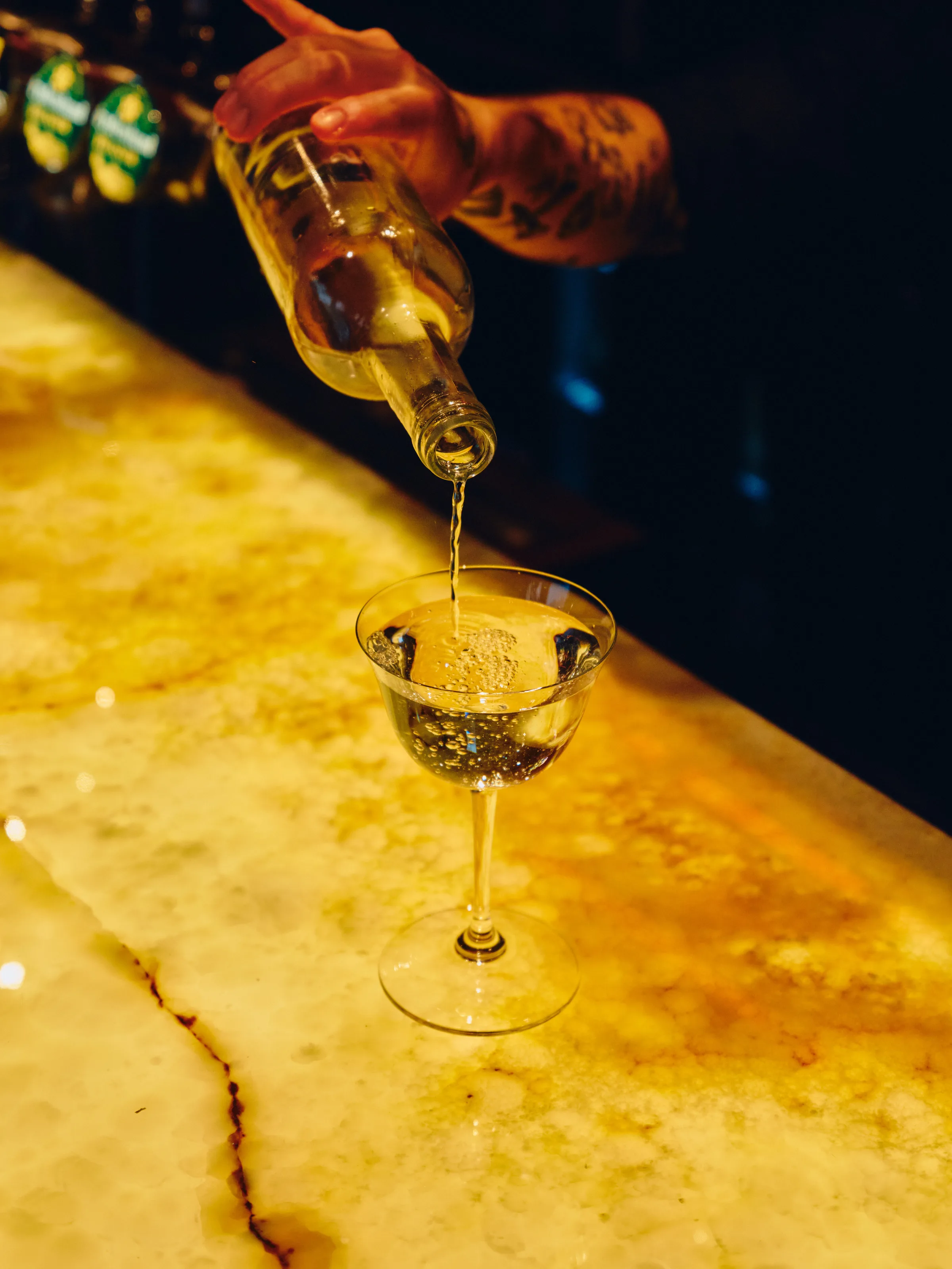 Bartender heller cocktail i glass på gyllen marmorbardisk