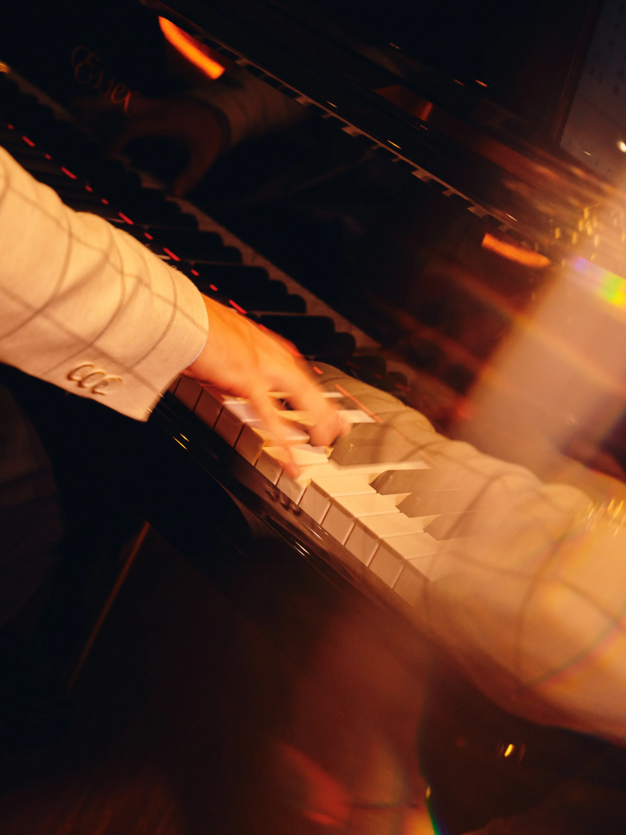 Close-up of a hand playing piano in warm golden light